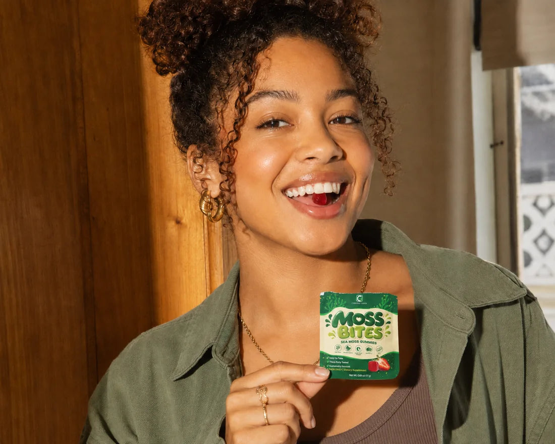 A smiling woman holding up a Moss Bites daily pack after eating a gummy